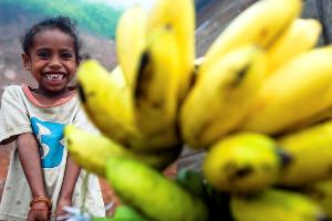 A young girl sells bananas along the road